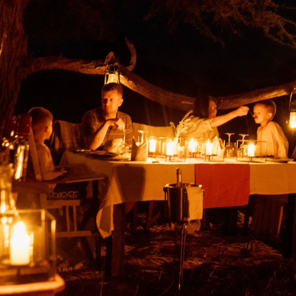 Family enjoying a lantern-lit bush dinner on safari